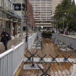 
              Restaurant tables are turned upside down as a pedestrian walks past the patio in downtown Halifax ahead of Hurricane Fiona making landfall on Friday, Sept. 23, 2022.  (Darren Calabrese /The Canadian Press via AP)
            
