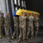 
              Servicemen carry the coffin of Olga Simonova, 34, a Russian woman who was killed in the Donetsk region while fighting on Ukraine's side in the war with her native country, in a crematorium in Kyiv, Ukraine, Saturday, Sept. 17, 2022. (AP Photo/Roman Hrytsyna)
            