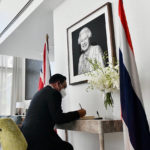
              In this photo release by Government Spokesman Office, Thailand Defense Minister Prayuth Chan-ocha, currently suspended as Thailand's prime minister while a court decides a legal challenge against him, signs a book of condolence in front of a picture of Queen Elizabeth II at British Ambassador's Residence in Bangkok, Thailand, Friday, Sept. 9, 2022. Queen Elizabeth II, Britain's longest-reigning monarch and a rock of stability across much of a turbulent century, died Thursday Sept. 8, 2022, after 70 years on the throne. She was 96. (Thailand Government Spokesman Office via AP)
            