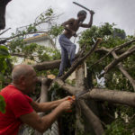 Residents cut away tree branches felled by Hurricane Ian in Havana, Cuba, Wednesday, Sept. 28, 2022. Cuba remained in the dark early Wednesday after Ian knocked out its power grid and devastated some of the country's most important tobacco farms when it hit the island's western tip as a major storm. (AP Photo/Ismael Francisco)