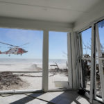 
              A U.S. Coast Guard helicopter takes off on Sanibel Island, Fla., with people affected by Hurricane Ian, as seen from inside a damaged home, Friday, Sept. 30, 2022. (AP Photo/Steve Helber)
            