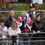 
              Members of the public, one of them holding a Paddington Bear toy, outside Buckingham Palace wait to watch Queen Elizabeth II funeral procession, in central London Monday, Sept. 19, 2022. The Queen, who died aged 96 on Sept. 8, will be buried at Windsor alongside her late husband, Prince Philip, who died last year. (AP Photo/Christophe Ena, Pool)
            