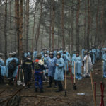 
              Emergency workers have a rest during the exhumation in the recently retaken area of Izium, Ukraine, Friday, Sept. 16, 2022. Ukrainian authorities discovered a mass burial site near the recaptured city of Izium that contained hundreds of graves. It was not clear who was buried in many of the plots or how all of them died, though witnesses and a Ukrainian investigator said some were shot and others were killed by artillery fire, mines or airstrikes. (AP Photo/Evgeniy Maloletka)
            