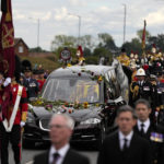 
              Flowers cover the hearse carrying the coffin of Queen Elizabeth II as it arrives on the Albert Road outside Windsor Castle in Windsor, England, Monday, Sept. 19, 2022. The Queen, who died aged 96 on Sept. 8, will be buried at Windsor alongside her late husband, Prince Philip, who died last year. (AP Photo/Alastair Grant, Pool)
            