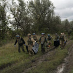 
              Ukrainian national guard servicemen carry bags containing the bodies of two Ukrainian soldiers in an area near the border with Russia, in Kharkiv region, Ukraine, Monday, Sept. 19, 2022. In this operation seven bodies of Ukrainian soldiers were recovered from what was the battlefield in recent months. (AP Photo/Leo Correa)
            
