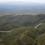 
              The International border wall, with Mexico to the top, abruptly ends as it cuts through the base of the Baboquivari Mountains, Thursday, Sept. 8, 2022, near Sasabe, Ariz. The desert region located in the Tucson sector just north of Mexico is one of the deadliest stretches along the international border with rugged desert mountains, uneven topography, washes and triple-digit temperatures in the summer months. The border consists of wall, bollards or no barrier at all and has become a corridor of choice for those who don't turn themselves in right after crossing or apply for protection legally. (AP Photo/Giovanna Dell'Orto)
            
