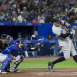 
              New York Yankees' Aaron Judge hits a two-run home run, his 61st homer of the season, next to Toronto Blue Jays catcher Danny Jansen during the seventh inning of a baseball game Wednesday, Sept. 28, 2022, in Toronto. (Nathan Denette/The Canadian Press via AP)
            
