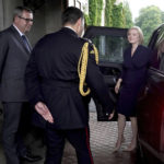 
              Newly elected leader of the Conservative party Liz Truss  is greeted by Queen Elizabeth II's Equerry Lieutenant Colonel Tom White and her Private Secretary Sir Edward Young as she arrives at Balmoral for an audience with Queen Elizabeth II where she will be invited to become Prime Minister and form a new government, in Aberdeenshire, Scotland, Tuesday, Sept. 6, 2022. (Andrew Milligan/Pool Photo via AP)
            