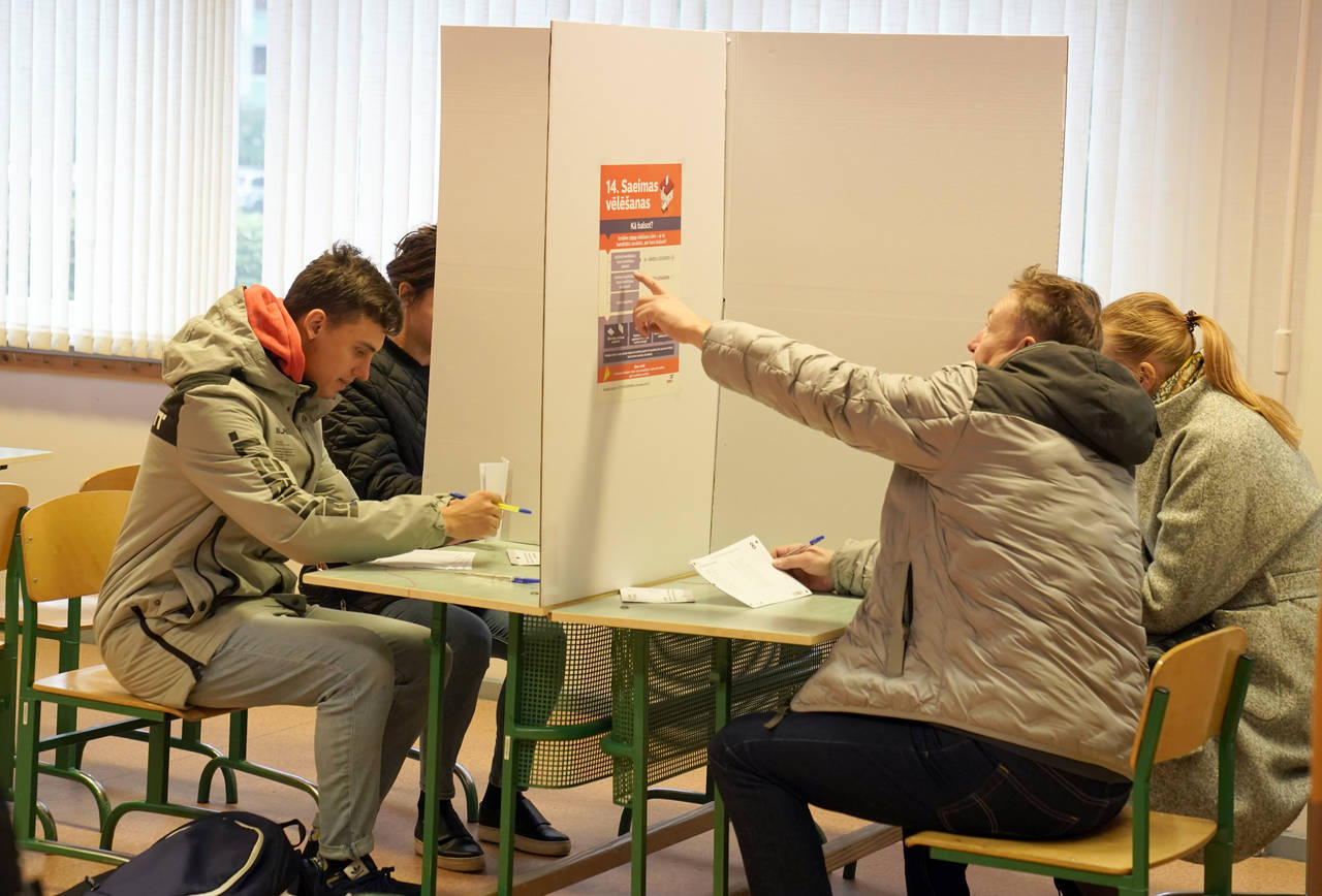 Latvians mark their ballots at a polling station during general elections in Riga, Latvia, Saturday...