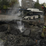 
              Firefighters and police officers work on a site where an explosion created a crater on the street after a Russian attack in Dnipro, Ukraine, Monday, Oct. 10, 2022. (AP Photo/Leo Correa)
            