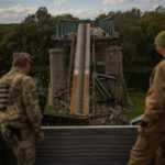
              Ukrainian soldiers remove metal structure pieces as they work on a bridge damaged during fighting with Russian troops in Izium, Ukraine, Monday, Oct. 3, 2022. (AP Photo/Francisco Seco)
            