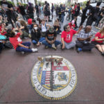 
              Protesters sit on the street outside City Hall during the Los Angeles City Council meeting Tuesday, Oct. 11, 2022 in Los Angeles. (AP Photo/Ringo H.W. Chiu)
            