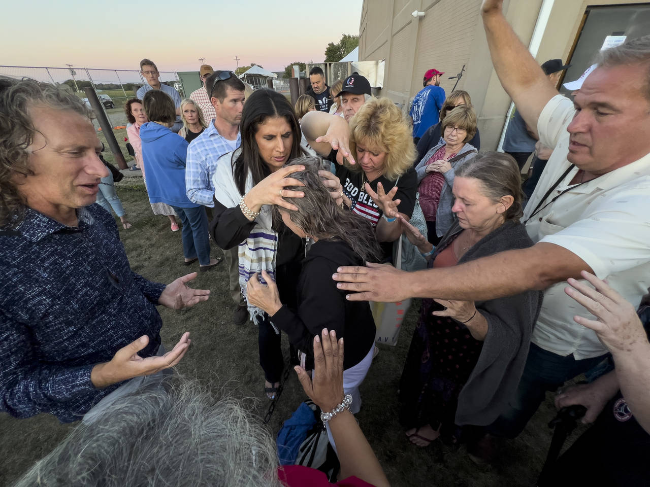 Amanda Grace of Ark of Grace Ministries and a group of people gather in prayer around a woman for t...