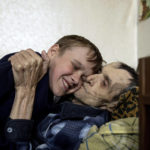 
              Mykola Svyryd, 70, hugs his son Bohdan, 13, in a shelter for injured and homeless people in Izium, Ukraine, Monday, Sept. 26, 2022. A young Ukrainian boy with disabilities, 13-year-old Bohdan, is now an orphan after his father, Mykola Svyryd, was taken by cancer in the devastated eastern city of Izium. (AP Photo/Evgeniy Maloletka)
            