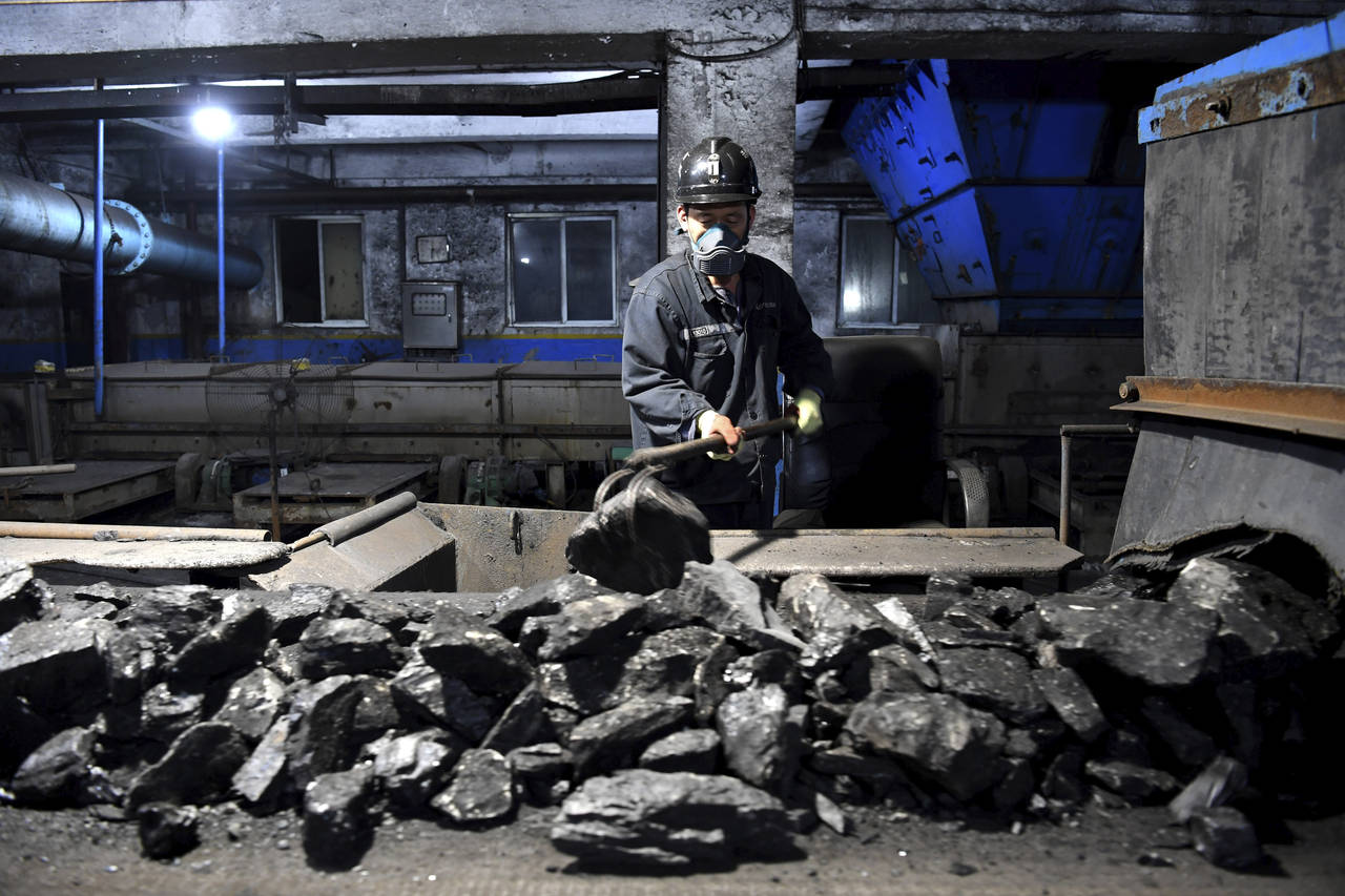 In this photo released by Xinhua News Agency, a worker sort coals at Qianyingzi coal mine in Suzhou...
