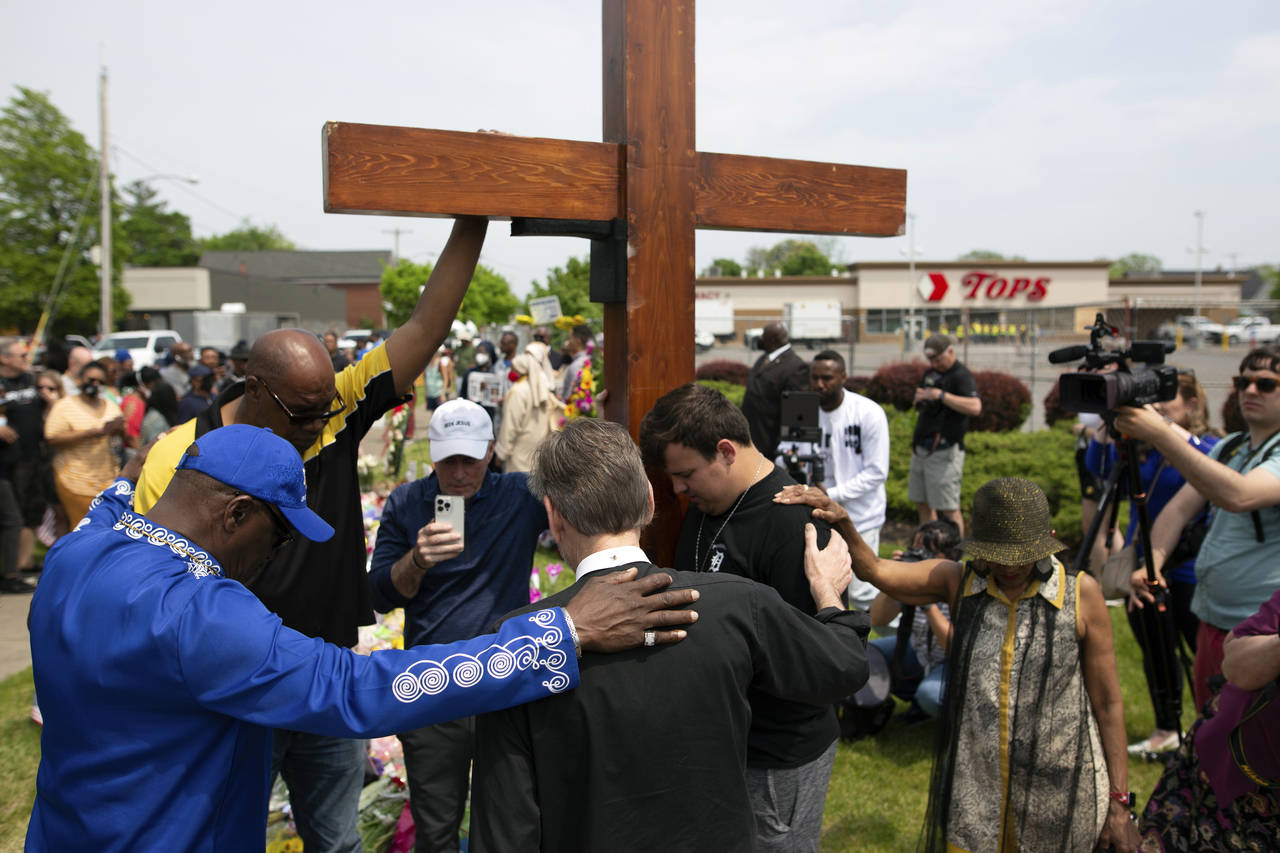 FILE - A group prays at the site of a memorial for the victims of the Buffalo supermarket shooting ...