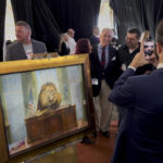 
              Roger Stone poses for photographs as a painting by Elisabeth Miller titled “Lion of Judah on the Resolute Desk” is displayed during the ReAwaken America Tour at Cornerstone Church in Batavia, N.Y., Friday, Aug. 12, 2022. While smaller in scale, the ReAwaken shows are similar in tone to the rallies former President Trump holds. Grievance and contempt for government institutions are regular themes. (AP Photo/Carolyn Kaster)
            