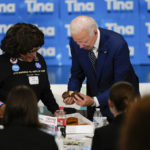 
              President Joe Biden picks a doughnut to eat as Rosa Colquitt, Vice Chair of the Democratic Party of Oregon, left, looks on during a grassroots volunteer event with the Oregon Democrats at the SEIU Local 49 in Portland, Ore. Friday, Oct. 14, 2022. (AP Photo/Carolyn Kaster)
            