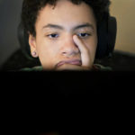 
              Miles Fallon works at his computer in his Chicago home Wednesday, Oct. 12, 2022. His mother, Marla Williams, initially supported the Chicago Public Schools decision to instruct students online during the fall of 2020. Williams, a single mother, has asthma, as do her two children. While she was working, she enlisted her father, a retired teacher, to supervise her children’s studies. (AP Photo/Charles Rex Arbogast)
            