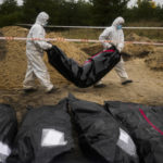 
              Members of a forensic team carry a plastic bag with a body inside as they work in an exhumation in a mass grave in Lyman, Ukraine, Tuesday, Oct. 11, 2022. (AP Photo/Francisco Seco)
            