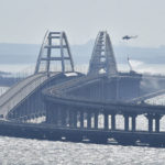 
              A helicopter drops water to stop fire on Crimean Bridge connecting Russian mainland and Crimean peninsula over the Kerch Strait, in Kerch, Saturday, Oct. 8, 2022. Russian authorities say a truck bomb has caused a fire and the collapse of a section of a bridge linking Russia-annexed Crimea with Russia. The bridge is a key supply artery for Moscow's faltering war effort in southern Ukraine. (AP Photo)
            