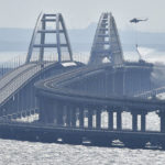
              A helicopter drops water to stop fire on Crimean Bridge connecting Russian mainland and Crimean peninsula over the Kerch Strait, in Kerch, Saturday, Oct. 8, 2022. Russian authorities say a truck bomb has caused a fire and the collapse of a section of a bridge linking Russia-annexed Crimea with Russia. The bridge is a key supply artery for Moscow's faltering war effort in southern Ukraine. (AP Photo)
            
