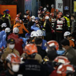 
              Rescue workers try to carry victims near the scene where scores of people died and were injured in Seoul, South Korea, Sunday, Oct. 30, 2022. Witnesses say the nightmarish scene intensified as people performed CPR on the dying and carried limp bodies to ambulances, while dance music pulsed from garish clubs lit in bright neon. Others tried desperately to pull out those who were trapped underneath the crush of people, but failed because too many in the crowd had fallen on top of them. (AP Photo/Lee Jin-man)
            