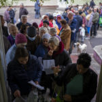 
              People queue to receive a daily ration of bread in a school in Mykolaiv, Tuesday, Oct. 25, 2022. Mykolaiv residents pick up bread from the only food distribution point in Varvarivka, a Mykolaiv district where thousands of people live. One person is allowed to receive free bread just once in three days. (AP Photo/Emilio Morenatti)
            
