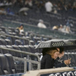
              Baseball fans wait out a rain delay for Game 5 of an American League Division baseball series between the New York Yankees and the Cleveland Guardians, Monday, Oct. 17, 2022, in New York. (AP Photo/Seth Wenig)
            
