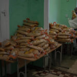 
              Volunteers distribute bread rations to civilians waiting at a public school in MykolaivTuesday, Oct. 25, 2022. Mykolaiv residents pick up bread from the only food distribution point in Varvarivka, a Mykolaiv district where thousands of people live. One person is allowed to receive free bread just once in three days. (AP Photo/Emilio Morenatti)
            