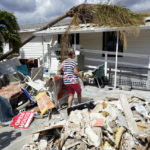 
              CORRECTS SPELLING OF LAST NAME TO ANDERSON, NOT ANDREWS - Nancy Anderson walks back to her mobile home, Thursday, Oct. 6, 2022, in Fort Myers Beach, Fla., that was damaged by Hurricane Ian, (AP Photo/Wilfredo Lee)
            