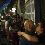 
              A couple kisses outside a bar at the Lapa neighborhood of Rio de Janeiro on Saturday, Oct. 1, 2022, one day before Brazil goes to the polls in a general election. (AP Photo/Matias Delacroix)
            