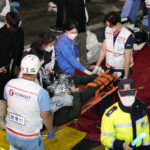 
              Rescue workers carry injured people on the street near the scene in Seoul, South Korea, Sunday, Oct. 30, 2022. South Korean officials say at least 120 people were killed and 100 more were injured as they were crushed by a large crowd pushing forward on a narrow street during Halloween festivities in the capital of Seoul. Choi Seong-beom, chief of Seoul’s Yongsan fire department, said the death toll could rise, saying that an unspecified number among the injured were in critical conditions. (AP Photo/Lee Jin-man)
            