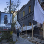 
              A man passes by a building damaged in a Russian rocket attack a week ago, in central Kyiv, Ukraine, Sunday, Oct. 16, 2022. (AP Photo/Efrem Lukatsky)
            