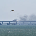 
              A helicopter drops water to stop fire on Crimean Bridge connecting Russian mainland and Crimean peninsula over the Kerch Strait, in Kerch, Crimea, Saturday, Oct. 8, 2022. Russian authorities say a truck bomb has caused a fire and the collapse of a section of a bridge linking Russia-annexed Crimea with Russia. The bridge is a key supply artery for Moscow's faltering war effort in southern Ukraine. (AP Photo)
            