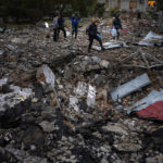 
              People walk on the rubble after a Russian missile hit a nearby block of apartments in Mykolaiv, Sunday, Oct. 23, 2022. (AP Photo/Emilio Morenatti)
            