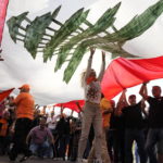 
              Supporters of Lebanese President Michel Aoun hold up a giant Lebanese flag as he delivers a speech outside the presidential palace in Baabda, east of Beirut, Lebanon, Sunday, Oct. 30, 2022. Aoun left Lebanon's presidential palace Sunday marking the end of his six-year term without a replacement, leaving the small nation in a political vacuum that is likely to worsen its historic economic meltdown. (AP Photo/Bilal Hussein)
            