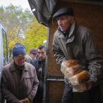 
              A volunteer unload bread as local residents wait for free bread distribution in Bakhmut, the site of the heaviest battle against the Russian troops in the Donetsk region, Ukraine, Friday, Oct. 28, 2022. (AP Photo/Efrem Lukatsky)
            