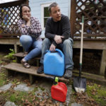 
              Lucinda Tyler and Aaron Raymo sit outside their home with fuel containers they used to fill their heating oil tank at their home, Wednesday, Oct. 5, 2022 in Jay, Maine. The couple shopped around for the best prices and bought heating oil 5 gallons at a time throughout the summer whenever they had any extra money. (AP Photo/Robert F. Bukaty)
            