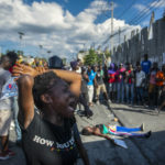 
              FILE - A woman cries near the body of another woman fatally shot by the police during a protest demanding the resignation of Prime Minister Ariel Henry in the Delmas area of Port-au-Prince, Haiti, Monday, Oct. 10, 2022. (AP Photo/Odelyn Joseph, File)
            