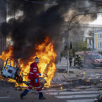 
              A medical worker runs past a burning car after a Russian attack in Kyiv, Ukraine, Monday, Oct. 10, 2022. The Russian missiles that rained down Monday on cities across Ukraine, bringing fear and destruction to areas that had seen months of relative calm, are an escalation in Moscow's war against its neighbor. But military analysts say it’s far from clear whether the strikes mark a turning point in a war that has killed thousands of Ukrainians and sent millions fleeing from their homes. (AP Photo/Roman Hrytsyna)
            