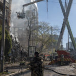 
              Firefighters work after a drone fired on buildings in Kyiv, Ukraine, Monday, Oct. 17, 2022. Waves of explosive-laden suicide drones struck Ukraine's capital as families were preparing to start their week early Monday, the blasts echoing across Kyiv, setting buildings ablaze and sending people scurrying to shelters. (AP Photo/Roman Hrytsyna)
            