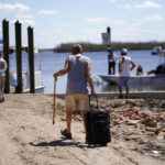 
              Residents who rode out the storm arrive at a dock to evacuate by boat in the aftermath of Hurricane Ian, on Pine Island in Florida's Lee County, Sunday, Oct. 2, 2022. The only bridge to the island is heavily damaged so it can only be reached by boat or air. (AP Photo/Gerald Herbert)
            