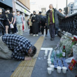 
              A man bows to pay tribute for victims near the scene of a deadly accident in Seoul, South Korea, Sunday, Oct. 30, 2022, following Saturday night's Halloween festivities. A mass of mostly young people among tens of thousands who gathered to celebrate Halloween in Seoul became trapped and crushed as the crowd surged into a narrow alley, killing dozens of people and injuring dozens of others in South Korea’s worst disaster in years. (AP Photo/Ahn Young-joon)
            