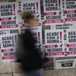 
              A woman walks past signs that read in Portuguese: "End the Agony, Bolsonaro Out," in Rio de Janeiro, Brazil, Friday, Sept. 30, 2022. Bolsonaro had held forward the possibility of a corruption-free Brazil, but once he took office he was ensnared in his own corruption scandals, including recent claims that members of his family bought dozens of properties in cash. (AP Photo/Matias Delacroix)
            