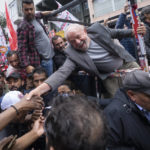 
              Brazil's former President Luiz Inacio Lula da Silva shakes hands with a supporter as he campaigns a day ahead of the country's general election, in Sao Paulo, Brazil, Saturday, Oct. 1, 2022. Polls show da Silva with a commanding lead that could possibly even give him a first-round victory. But even if that doesn’t happen, the vote itself marks an improbable political comeback for da Silva, a 76-year-old former metalworker who rose from poverty to the presidency — then just four years ago was jailed as part of a massive corruption investigation that targeted his Workers’ Party and upended Brazilian politics. (AP Photo/Victor R. Caivano)
            