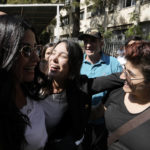 
              Sali Hafez, center, who broke into a BLOM Bank branch last month with others activists and forced bank employees to hand over $12,000 and the equivalent of about $1,000 in Lebanese pounds gestures as she leaves the Justice Palace, in Beirut, Lebanon, Thursday, Oct. 6, 2022. A Lebanese judge on Thursday fined and issued a six-month travel ban to Hafez who stormed her bank with a fake pistol and took her trapped savings to cover her sister's cancer treatment. (AP Photo/Hassan Ammar)
            