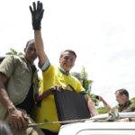 
              A member of a security detail holds a black bag with bulletproof plates as protection for Brazil's President Jair Bolsonaro as he greets supporters during a campaign rally in Praca da Liberdade or Liberty Square, in Belo Horizonte, Brazil, Saturday, Oct. 29, 2022. Bolsonaro is facing former President Luiz Inacio Lula da Silva in a runoff election set for Oct. 30. (AP Photo/Yuri Laurindo)
            