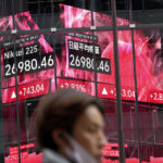 
              A person wearing a protective mask walks in front of an electronic stock board showing Japan's Nikkei 225 index at a securities firm Friday, Oct. 14, 2022, in Tokyo. Asian shares were mostly lower on Thursday after Wall Street benchmarks fell, reversing course after two days of gains. (AP Photo/Eugene Hoshiko, File)
            