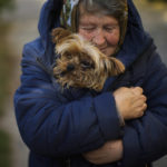 
              A woman warms her dog in Kivsharivka, Ukraine, Sunday, Oct. 16, 2022. As temperatures drop below freezing in eastern Ukraine, those who haven't fled from the heavy fighting, regular shelling and months of Russian occupation are now on the threshold of a brutal winter and digging in for the cold months. (AP Photo/Francisco Seco)
            